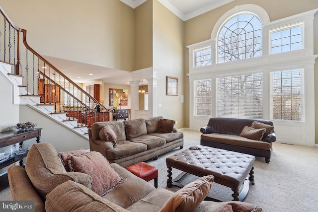 living area featuring carpet, stairs, decorative columns, and crown molding