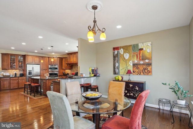 dining space featuring hardwood / wood-style flooring, baseboards, a chandelier, and recessed lighting