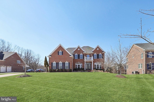 colonial house featuring a front yard, central AC unit, and brick siding