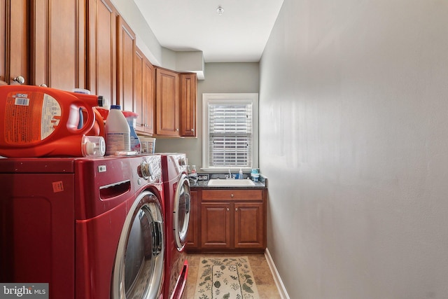 laundry area featuring washing machine and dryer, cabinet space, a sink, and baseboards