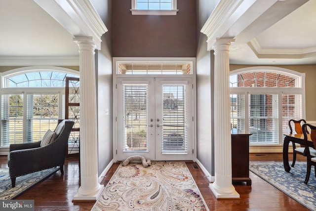 foyer featuring crown molding, a wealth of natural light, wood-type flooring, and decorative columns