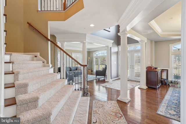 entryway with ornate columns, stairs, hardwood / wood-style floors, and crown molding