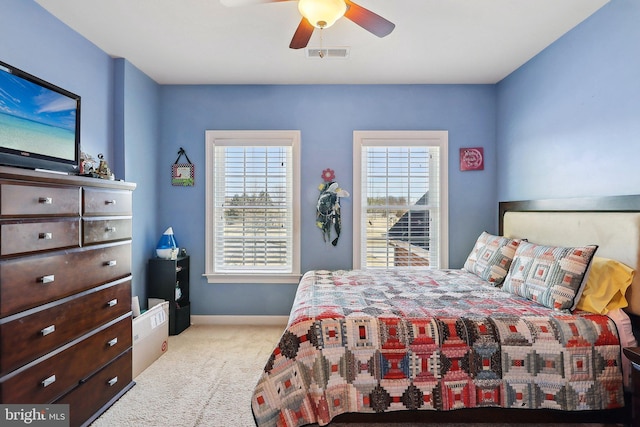 carpeted bedroom featuring a ceiling fan, multiple windows, visible vents, and baseboards