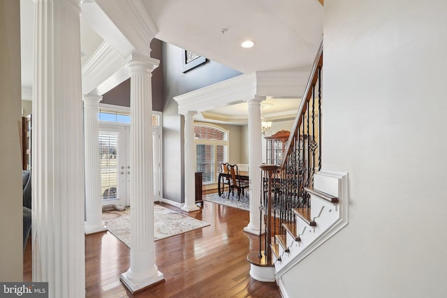 entryway featuring crown molding, decorative columns, hardwood / wood-style floors, baseboards, and stairs