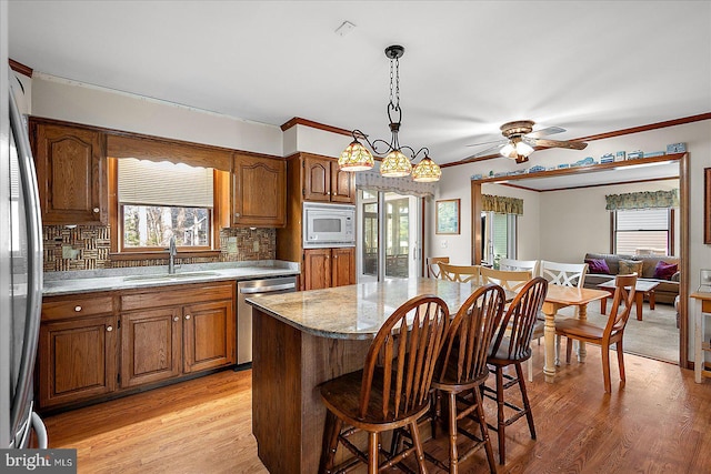 10133 Queens Cir, Ocean City, MD 21842 - kitchen featuring a breakfast bar, brown cabinets, appliances with stainless steel finishes, a sink, and light wood-type flooring