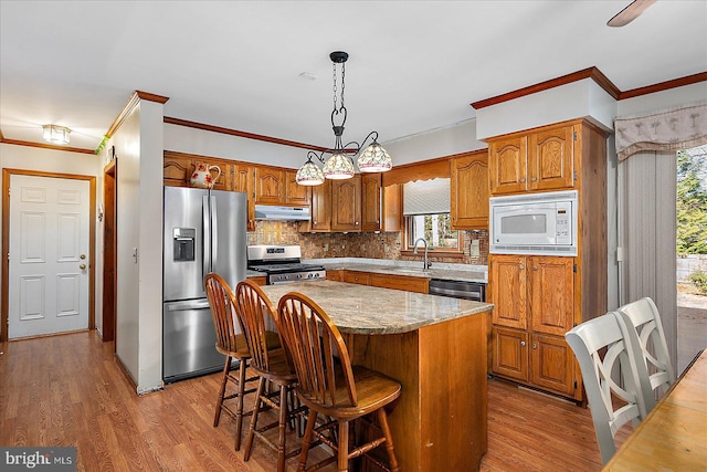 10133 Queens Cir, Ocean City, MD 21842 - kitchen with stainless steel appliances, under cabinet range hood, a kitchen island, a sink, and light wood-style floors
