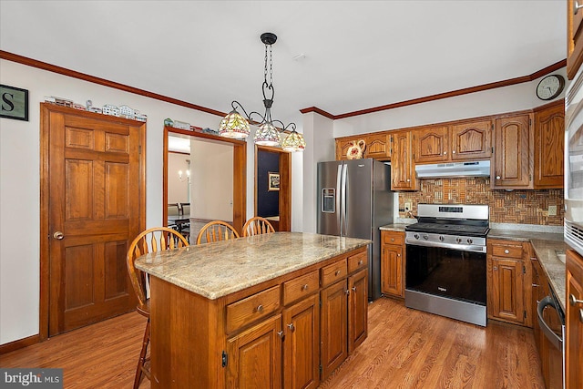 10133 Queens Cir, Ocean City, MD 21842 - kitchen with light wood-style flooring, under cabinet range hood, appliances with stainless steel finishes, and decorative backsplash