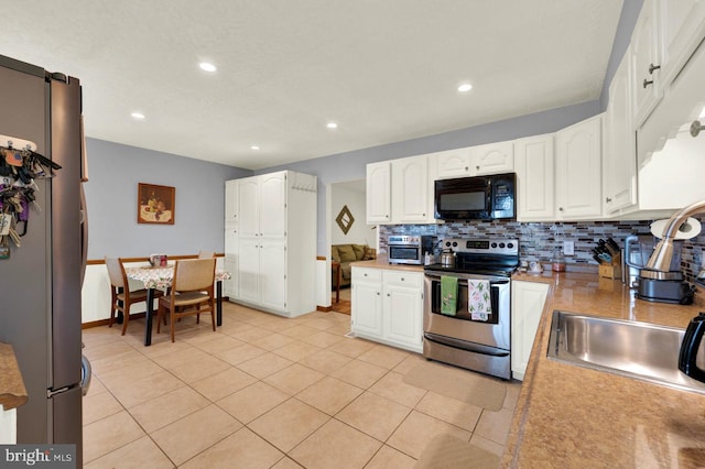 kitchen with white cabinetry, appliances with stainless steel finishes, light tile patterned floors, and backsplash