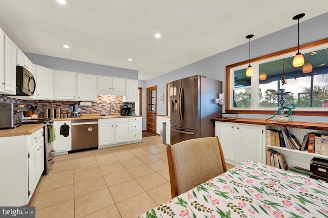 kitchen featuring white cabinetry, decorative light fixtures, light tile patterned floors, appliances with stainless steel finishes, and decorative backsplash