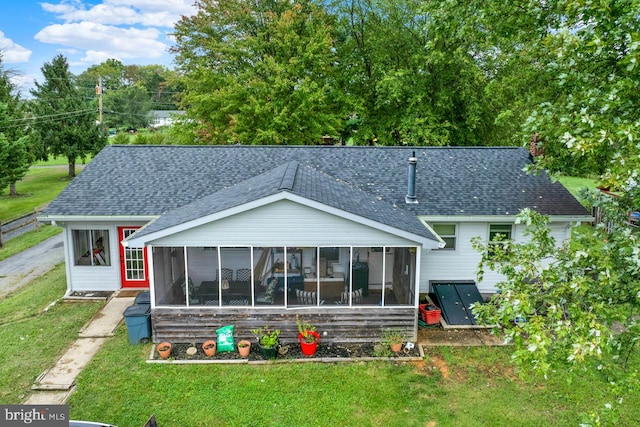 back of property featuring a sunroom and a lawn