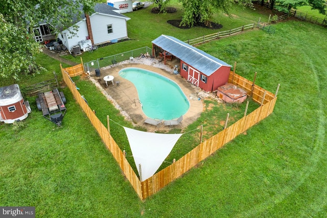 view of swimming pool with a storage shed and a lawn