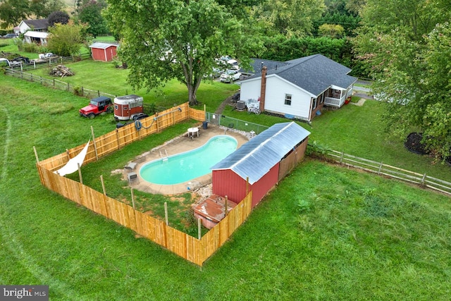 view of swimming pool with a storage shed and a lawn