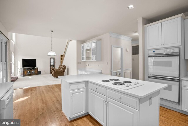 kitchen featuring glass insert cabinets, open floor plan, light countertops, white cabinets, and white appliances