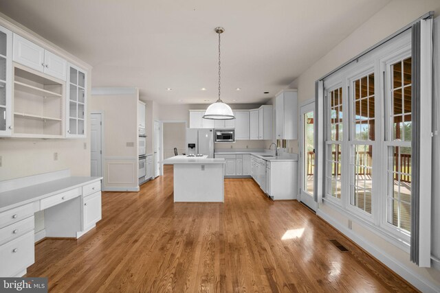 kitchen featuring visible vents, a center island, white cabinets, white appliances, and a sink