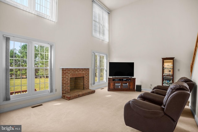 carpeted living area featuring visible vents, baseboards, a towering ceiling, and a fireplace