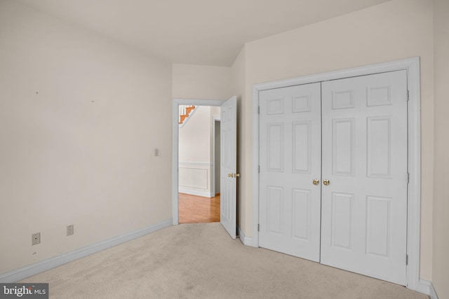 unfurnished bedroom featuring carpet flooring, baseboards, and a closet