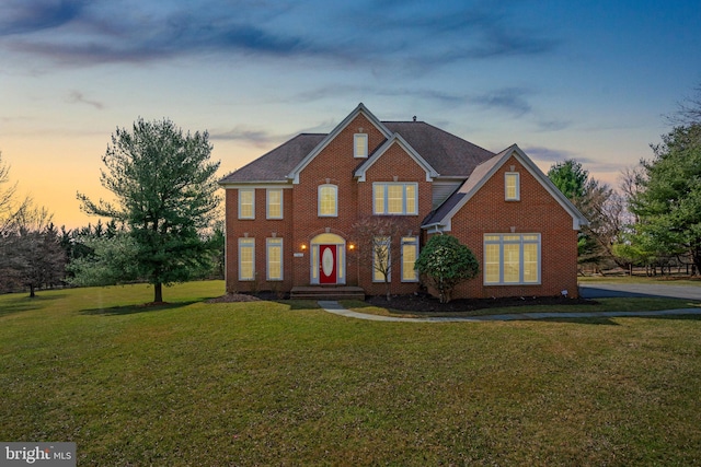 view of front of property with brick siding, a lawn, and a shingled roof