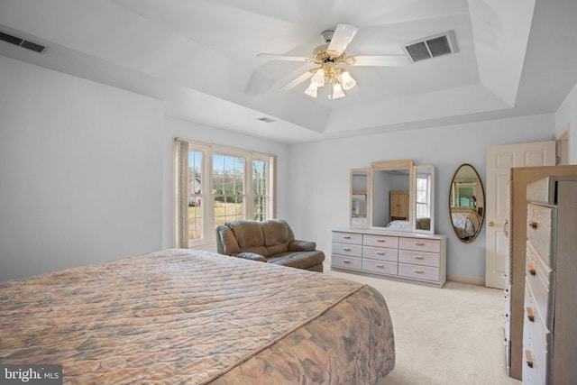 bedroom featuring a raised ceiling, light colored carpet, and visible vents