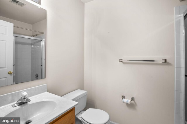 bathroom featuring a tile shower, visible vents, toilet, and vanity