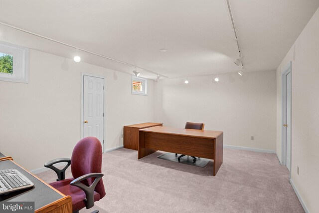 office space with light colored carpet, rail lighting, and baseboards