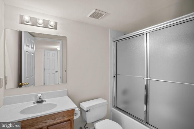 full bath with visible vents, toilet, vanity, and shower / bath combination with glass door