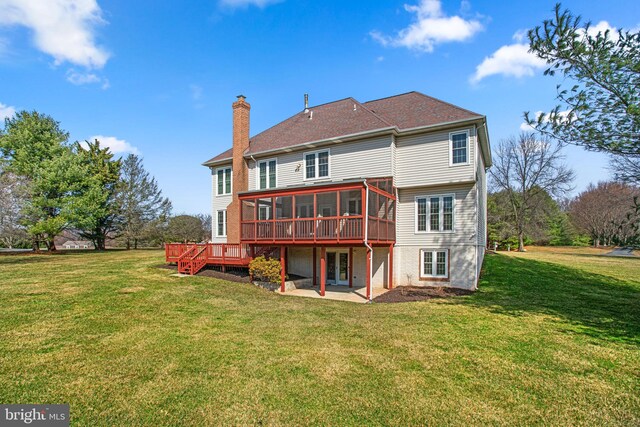 back of property featuring a lawn, a chimney, a deck, a sunroom, and a patio