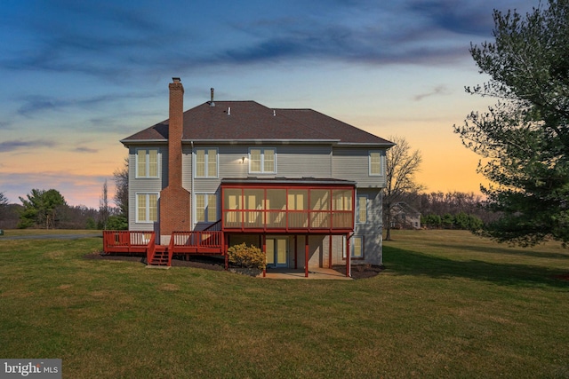 rear view of house with a deck, a patio, a yard, a sunroom, and a chimney