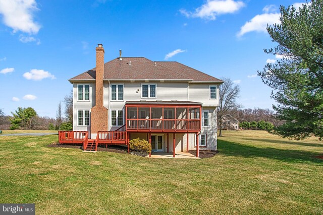 back of house featuring a wooden deck, a yard, a sunroom, a chimney, and a patio area