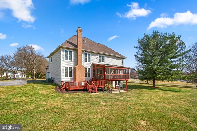 back of property featuring a lawn, a sunroom, cooling unit, a shingled roof, and a chimney