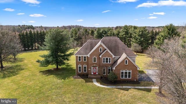 view of front of house with brick siding, a view of trees, and a front lawn