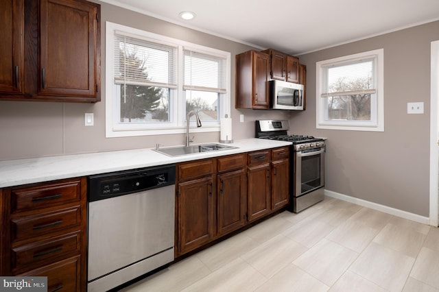 kitchen with sink, crown molding, dark brown cabinets, and stainless steel appliances