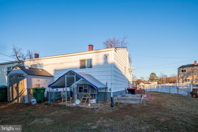 rear view of property with central AC, a storage shed, and a lawn