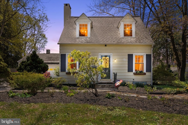 cape cod house featuring roof with shingles and a chimney