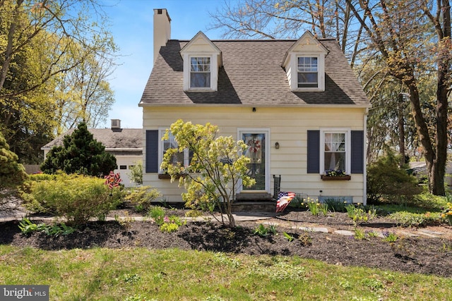 cape cod house featuring roof with shingles and a chimney