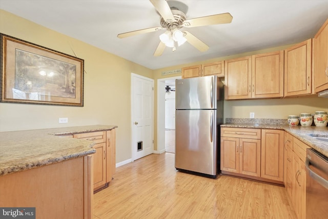 kitchen with a ceiling fan, light wood finished floors, appliances with stainless steel finishes, and light brown cabinetry