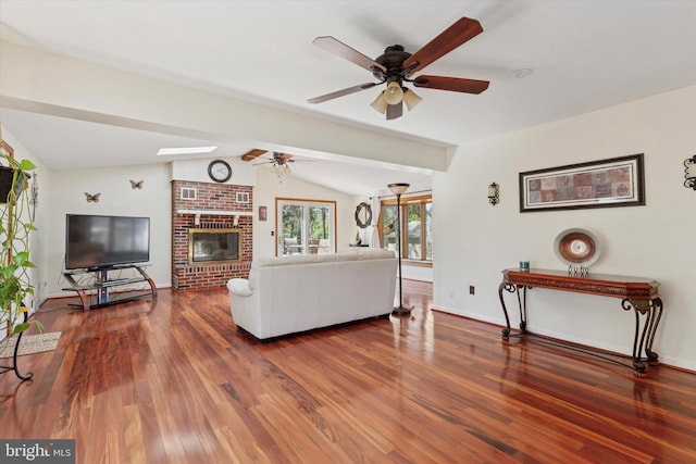 living room with baseboards, lofted ceiling with skylight, ceiling fan, and wood finished floors