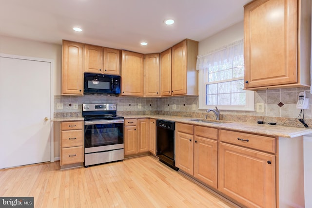 kitchen with sink, black appliances, tasteful backsplash, and light wood-type flooring