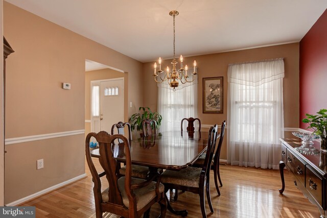 dining area featuring an inviting chandelier, a healthy amount of sunlight, and light hardwood / wood-style flooring