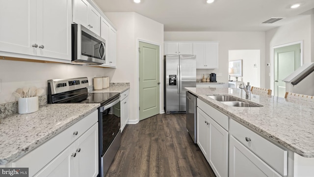 kitchen with an island with sink, white cabinetry, sink, stainless steel appliances, and dark wood-type flooring