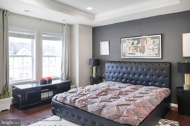 bedroom featuring visible vents, dark wood finished floors, a tray ceiling, crown molding, and recessed lighting