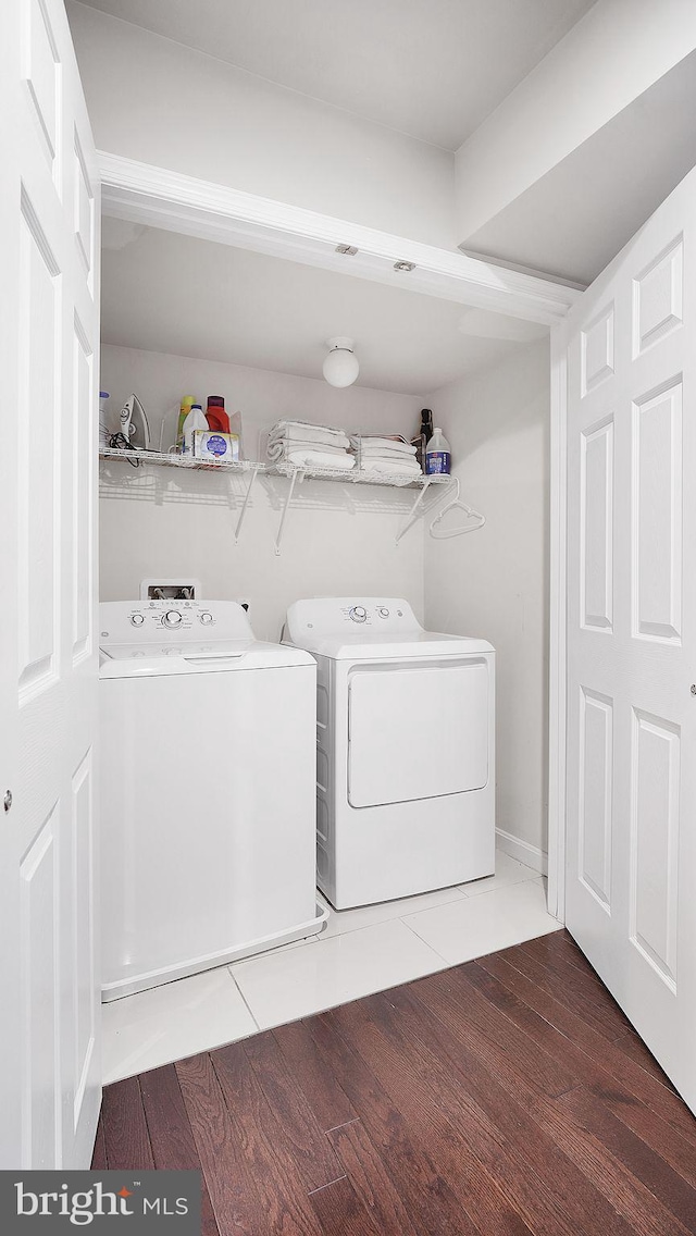 clothes washing area with laundry area, washing machine and dryer, and wood finished floors