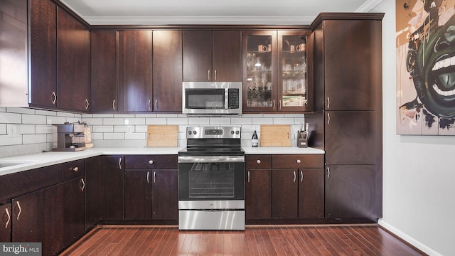 kitchen with decorative backsplash, stainless steel appliances, dark wood-type flooring, and light countertops