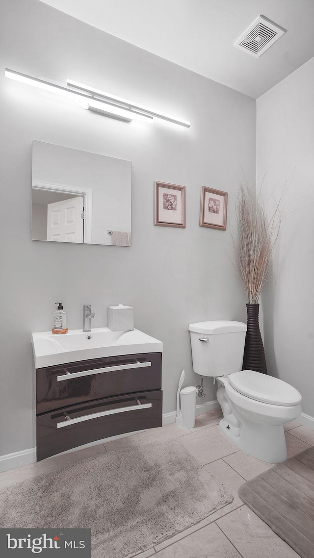 bathroom with visible vents, toilet, vanity, tile patterned flooring, and baseboards