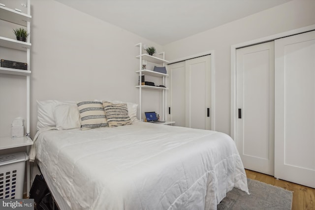 bedroom featuring multiple closets and light hardwood / wood-style flooring