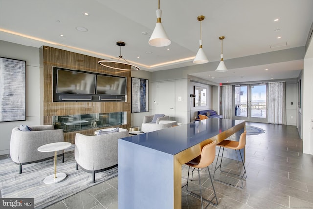 kitchen featuring a large fireplace, a kitchen bar, a tray ceiling, and decorative light fixtures