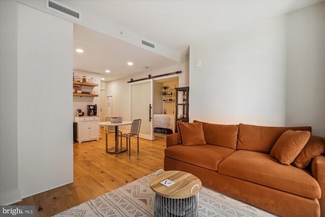 living room featuring a barn door and light hardwood / wood-style floors