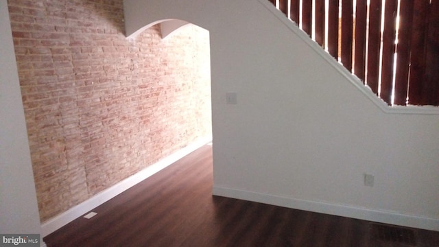 interior space with brick wall and dark hardwood / wood-style floors