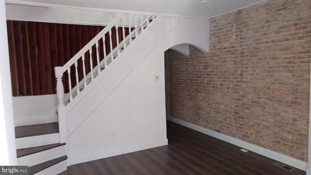 stairway featuring brick wall and hardwood / wood-style floors