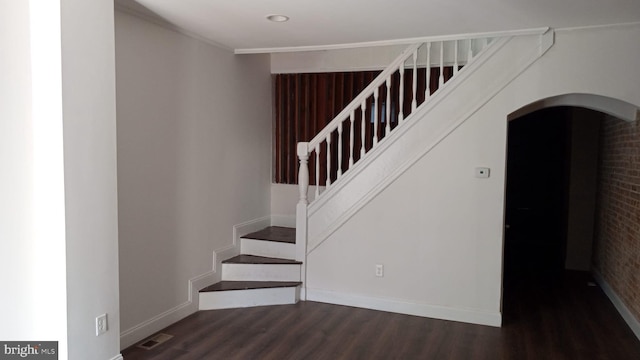 stairway with ornamental molding and hardwood / wood-style floors