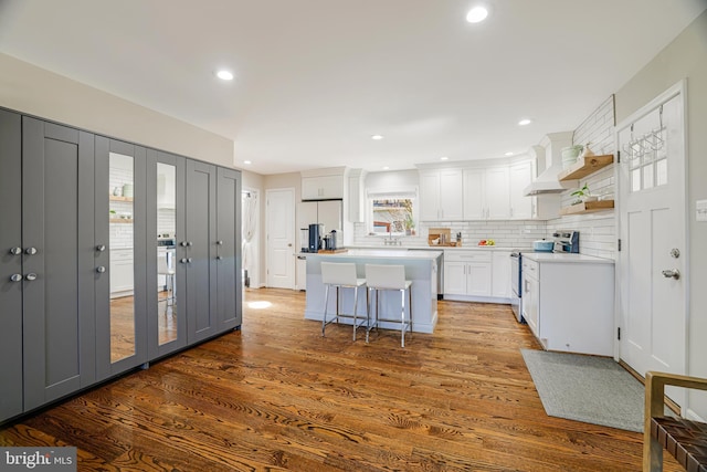 kitchen featuring a center island, wood-type flooring, white cabinets, stainless steel electric stove, and a kitchen breakfast bar